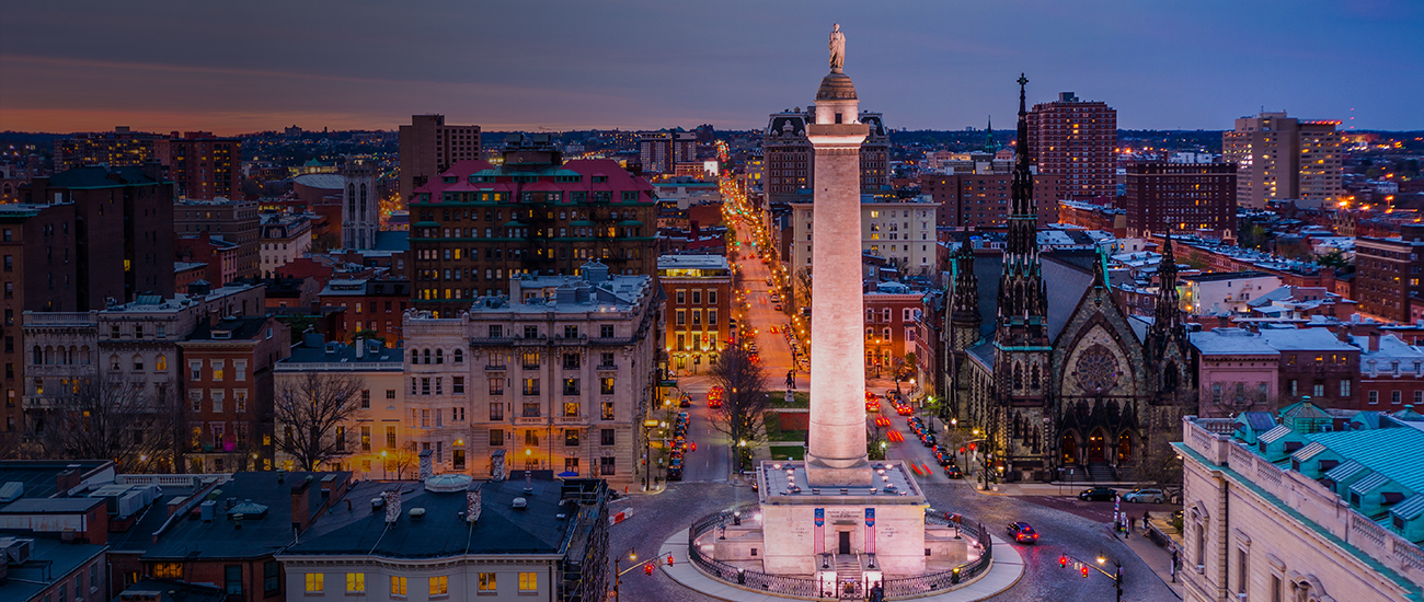 1. A tall monument stands prominently in the center of a bustling city, surrounded by buildings and pedestrians.